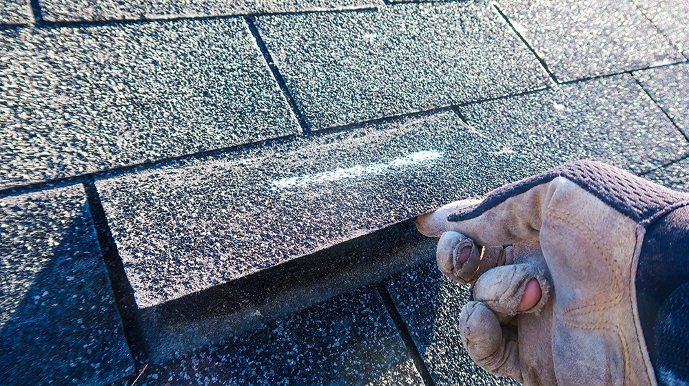 hand pulling up marked roof tile for inspection